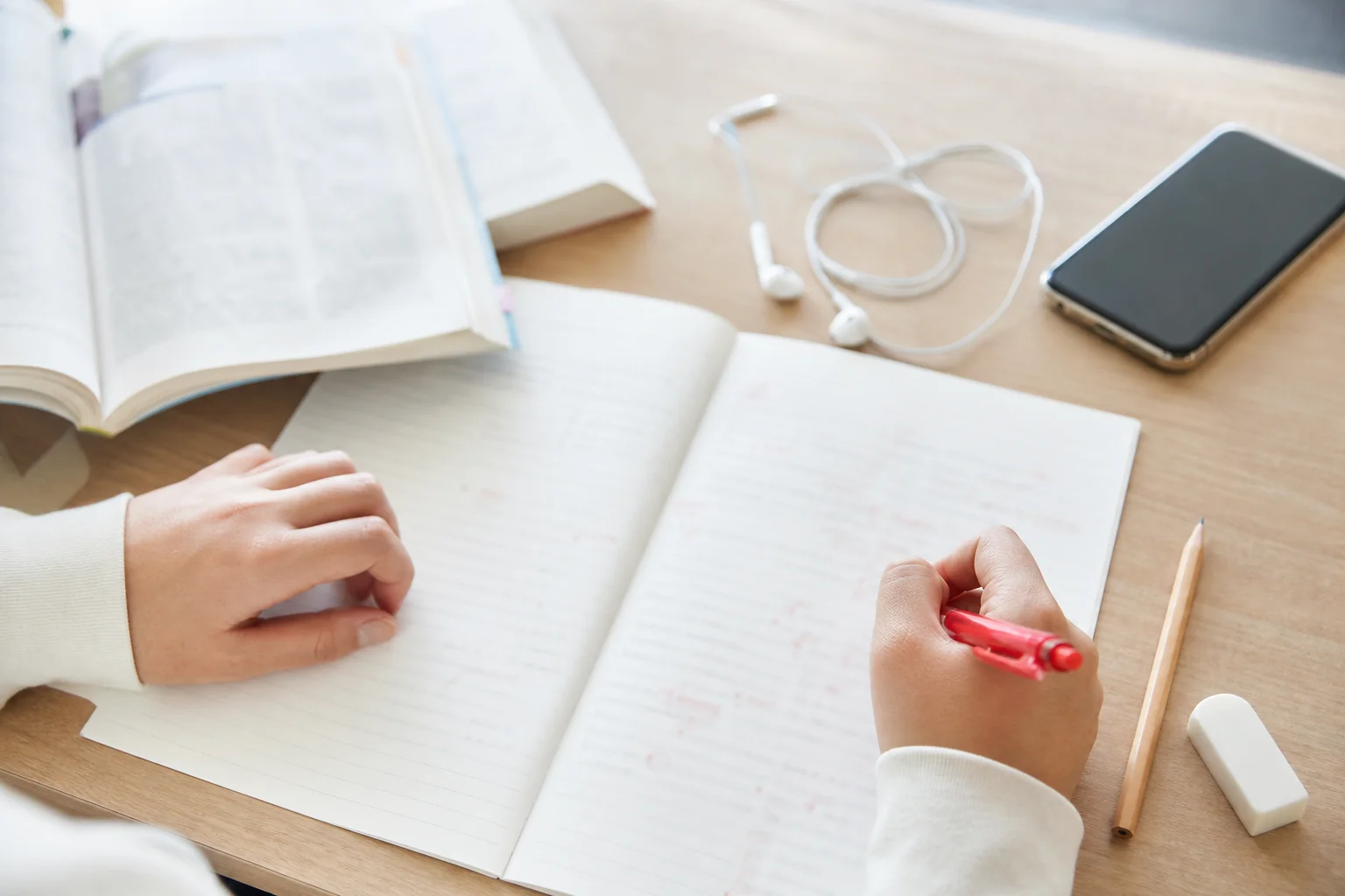 書き取りとテキストを照らし合わせ、ミスの理由を一言メモしているノートの手元